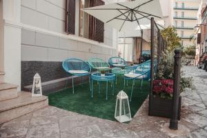 grupa krzeseł i parasol na patio w obiekcie Hotel Torino w mieście Brindisi