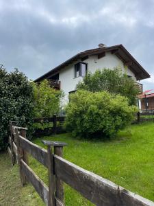 uma casa branca atrás de uma cerca de madeira em Architektenhaus mit Bergblick 220qm+Terasse/Garten em Irschenberg