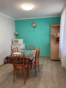 ALFA Szálláshely في Sándorfalva: غرفة طعام مع طاولة وكراسي وجدار أزرق