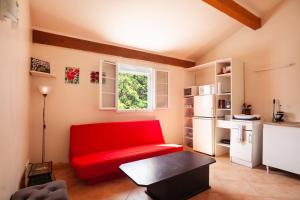 sala de estar con sofá rojo y ventana en Les collins du sud 2, en Peyrolles-en-Provence