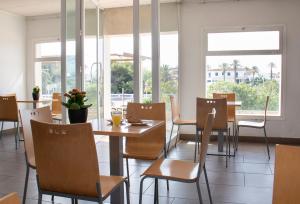 uma sala de jantar com mesas, cadeiras e janelas em Grupoandria Hotel Platja Gran em Ciutadella