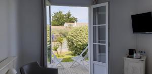 an open door to a balcony with chairs and a television at Thalacap Île de Ré - Thalasso & Spa in Ars-en-Ré