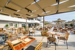 een patio met tafels, stoelen en parasols bij Nicolas Grand Suites, Adults Only in Kardamaina