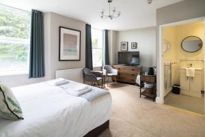 a hotel room with a bed and a desk and a television at Sleepy Puffin Guest House in Tenby