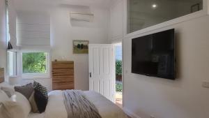 1 dormitorio con 1 cama y TV de pantalla plana en la pared en Peppercorn Cottage at Treetops Red Hill, en Red Hill