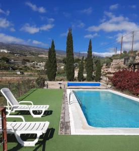 a swimming pool with two lounge chairs next to at Casa rural con vistas maravillosas en Arico in Sabina Alta