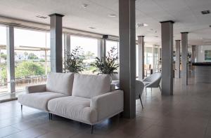białą kanapę siedzącą w pokoju z oknami w obiekcie Grupoandria Hotel Platja Gran w mieście Ciutadella