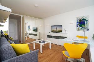 a living room with a couch and a table and yellow chairs at Strandsonne in List