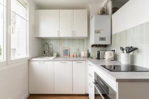 a white kitchen with white cabinets and a sink at Joli Appartement avec Garage sur l'Île de Nantes in Nantes