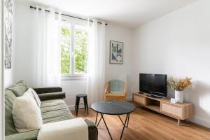a living room with a couch and a tv at Joli Appartement avec Garage sur l'Île de Nantes in Nantes
