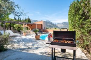 a barbecue grill in a backyard with a pool at Sunset Villa Can Calco in Moscari