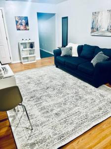 ein Wohnzimmer mit einem blauen Sofa und einem Teppich in der Unterkunft Spacious Cozy 2 Bedroom - Near EWR/NYC/OUTLET MALL in Newark