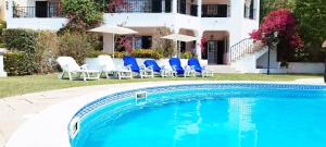 a swimming pool with blue chairs and a house at Sweet Home Lux Villa Vau in Portimão