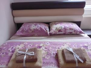a pink bed with two pillows and two towels at Apartmani Lazaro in Višegrad