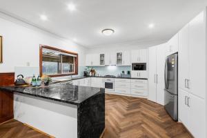 a kitchen with white cabinets and a black counter top at Escape farmhouse with cow birds lakes-SP group in Leopold