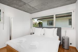 1 dormitorio blanco con 1 cama grande con almohadas blancas en Urban Cube mit Sauna, en Thun