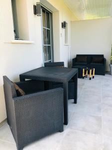 una mesa negra y sillas en un patio en Bel Air Studios-Terrasse couverte-Jardinet-Vue Pont de Normandie-Parking privé, en Honfleur