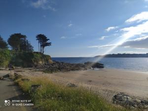 a beach with the sun shining on the water at Au coeur des Rias, studio Merrien proche de la mer in Moëlan-sur-Mer