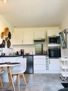a kitchen with white cabinets and a table and chairs at Bel Air Studios-Terrasse couverte-Jardinet-Vue Pont de Normandie-Parking privé in Honfleur