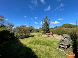 eine Parkbank in der Mitte eines Gartens in der Unterkunft Woodpecker Cottage in West Bretton