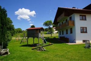 einen Spielplatz in einem Hof neben einem Haus in der Unterkunft Ferienwohnungen Paukner in Sankt Englmar