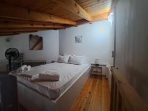 a bedroom with a bed with white sheets and wooden floors at Oceanides Apartments in Kourouta