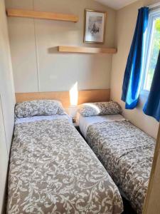 een kleine slaapkamer met 2 bedden en een raam bij Lola’s Caravan. Your home away from home. in Parkeston