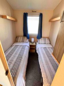 two beds in a small room with a window at Lola’s Caravan. Your home away from home. in Parkeston