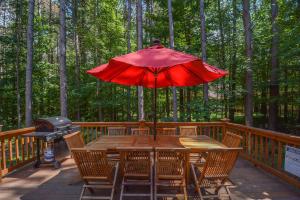 a wooden table with a red umbrella on a deck at Knotty Pines in Oakland