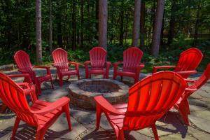 a group of red chairs around a fire pit at Knotty Pines in Oakland