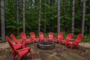 a group of red chairs around a fire pit at Knotty Pines in Oakland