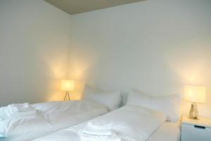 a white bed with white sheets and two lamps at Schlossblick in Spiez