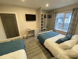 a bedroom with two beds and a desk with a television at Ard na Gréine in Stradbally