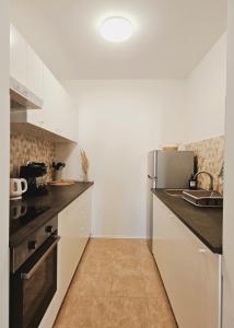 a kitchen with white cabinets and a refrigerator at Central Park Apartments in Koprivnica