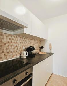 een keuken met witte kasten en een zwart aanrecht bij Central Park Apartments in Koprivnica