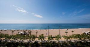 uma vista para uma praia com palmeiras e para o oceano em Hotel Internacional em Calella