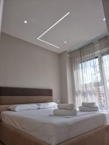 a bedroom with a bed with white sheets and a window at Anika Home Tirana 2 in Tirana