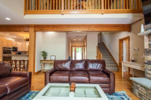 a living room with a leather couch and a table at Lakey McLakeHouse in Swanton