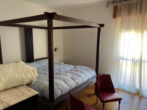 1 dormitorio con cama con dosel y silla en Casa al Mare en Buggerru
