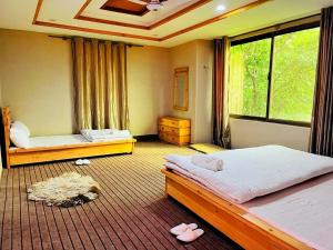 a bedroom with two beds and a large window at HIKK Inn in Skardu