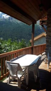 a white table and chairs on a wooden deck at Orion chalet facing the Meije - 10 persons in La Grave