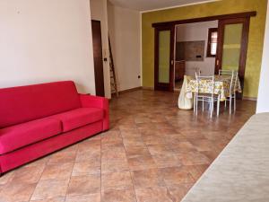 Casa vacanza Amanda في نيكوتيرا مارينا: غرفة معيشة مع أريكة حمراء وطاولة