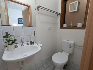 a white bathroom with a toilet and a sink at Studio 16 Wright Lodge in Adelaide