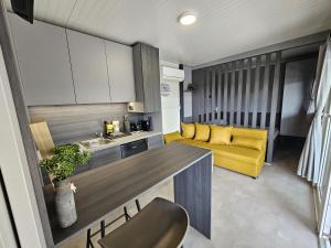 eine Küche und ein Wohnzimmer mit einem gelben Sofa in der Unterkunft BIG BERRY Kolpa - MerryBerry mobile house in Metlika