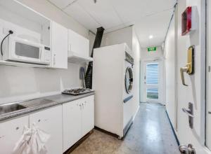 a white kitchen with a microwave and a refrigerator at Studio 15 Wright Lodge in Adelaide