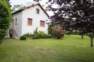 a white house with a tree and a grass yard at Le Refuge - Gîte Familial in Saint-Angel