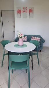 a table with chairs and a vase with flowers on it at La casa verde di Chicchi in Elmas