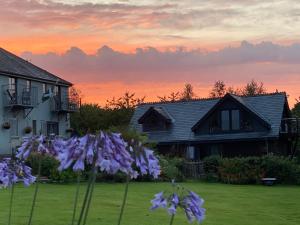 a yard with purple flowers in front of a house at Downton Lodge Country Bed and Breakfast and; Self Catering in Dartmouth