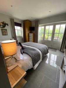 a bedroom with a bed with a lamp and windows at Downton Lodge Country Bed and Breakfast and; Self Catering in Dartmouth