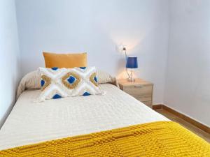 a bedroom with a bed with a yellow and white comforter at Estancia a 600m de la playa en el centro de Punta Umbria in Punta Umbría